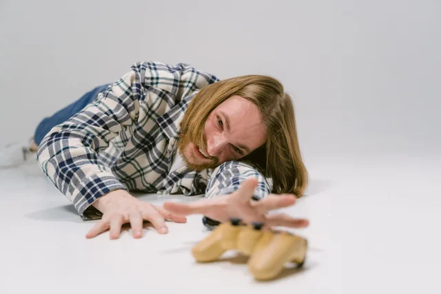 Man in plaid shirt reaching out to grab a gaming controller on a studio floor. Comparing gaming CPMs with qualified reach