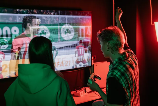 Two friends enjoying an exhilarating video game session indoors, captured with vibrant lighting. Creative localisation for game audiences