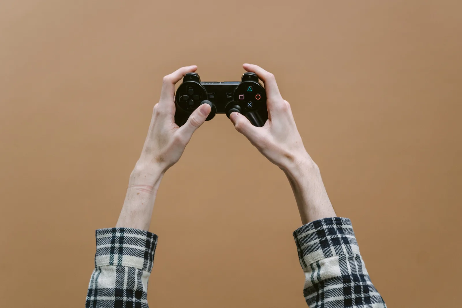 Close-up of hands holding a game controller against a brown background, perfect for gaming themes.