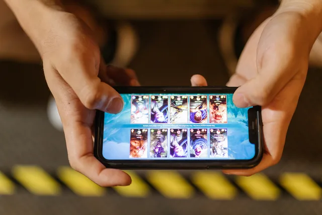 Close-up of hands playing a mobile game on a smartphone, showcasing the game's interface. Measuring viewability in a changing game environment