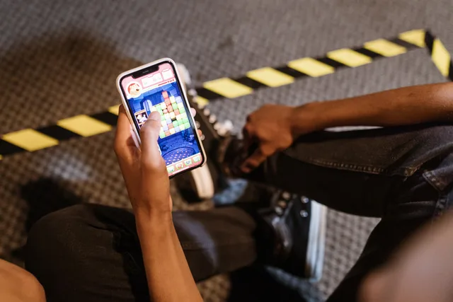A person playing a colorful puzzle game on a smartphone while seated indoors. Playable advertising